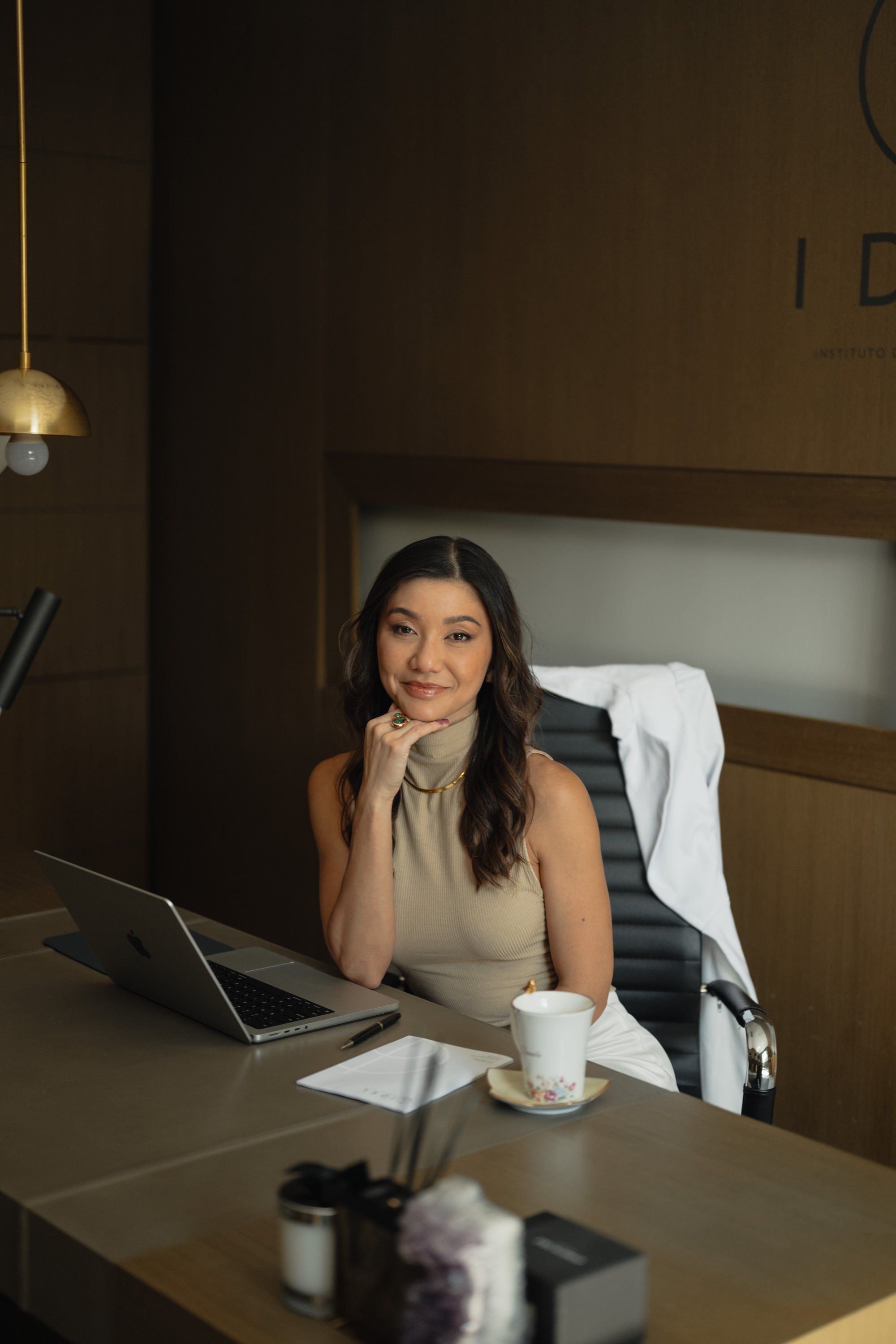 Dra. Danila Yoshioka, dermatologista em Curitiba, sentada à mesa do consultório